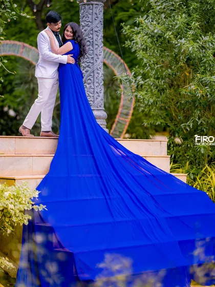 A romantic embrace on the steps. This low-angle shot emphasizes the height and drama of the scene, with the blue gown's train creating a waterfall effect.