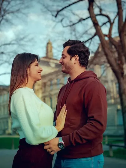An intimate portrait of a couple with classic European architecture behind them. The focus is on their loving gaze and the romantic atmosphere of the city.
