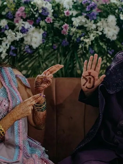 A fun, candid moment from a Sangeet where the groom playfully shows off his bride's initials in his Mehendi. These are the quirky, personal stories I love to capture.