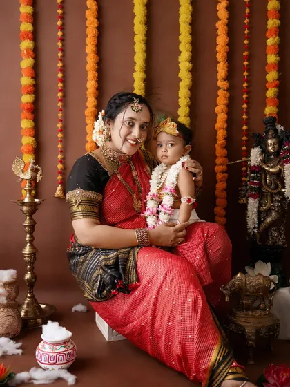 A classic portrait of a mother and child in their Janmashtami costumes, smiling for the camera.