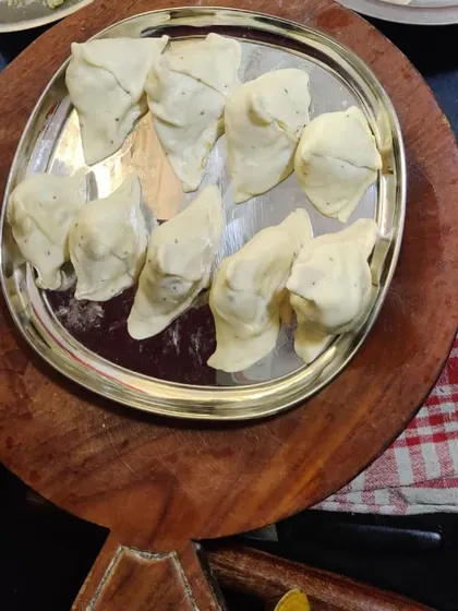 A tray of hand-folded samosas, filled with a spiced potato and pea mixture, ready for frying.