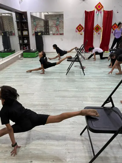 A wider view of our contemporary class, where students work on their splits with the help of chairs. This method allows for a safe and effective stretch.