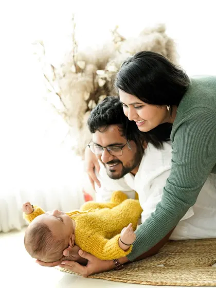 A bright and airy lifestyle newborn session. Here, new parents gaze lovingly at their baby in a relaxed, natural setting filled with soft light and textures.