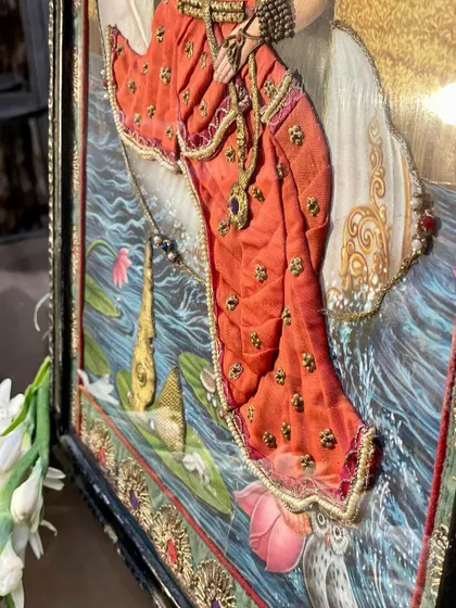 This close-up of a cloth oleograph shows the delicate embroidery on the subject's clothing and the water. This three-dimensional element, added to a vintage Raja Ravi Varma print, makes the scene come alive.