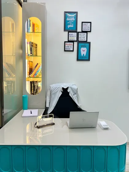 A closer look at the doctor's desk, showcasing the custom-built, back-lit shelving unit. This element provides functional storage for books and essentials while adding a warm, decorative glow to the consultation room.