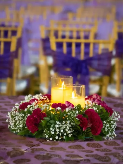 Every detail matters. For this anniversary dinner, the tables were adorned with beautiful centerpieces featuring candles surrounded by fresh red and white flowers, adding a touch of elegance to the seating arrangement.