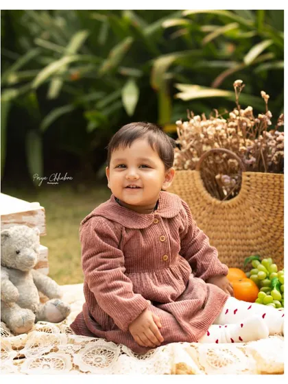 There's something special about an outdoor session, especially for a first birthday. We set up a cozy picnic with a teddy bear, fresh fruits, and soft blankets to create a dreamy, natural setting for this little one's milestone portraits in a Gurugram park.