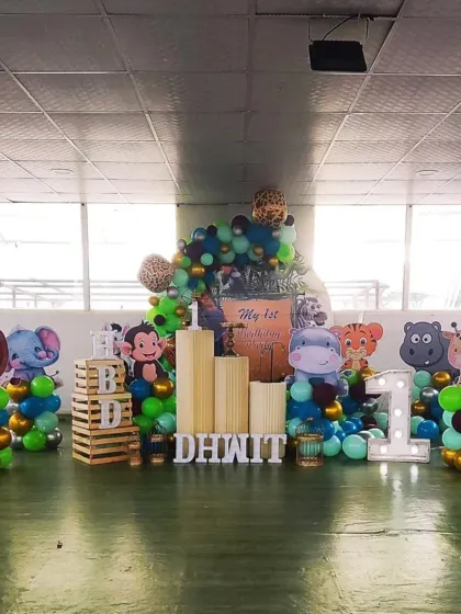 A jungle safari theme for Dhwit's first birthday, featuring cute cartoon animal cutouts and wooden crate props for a rustic feel.