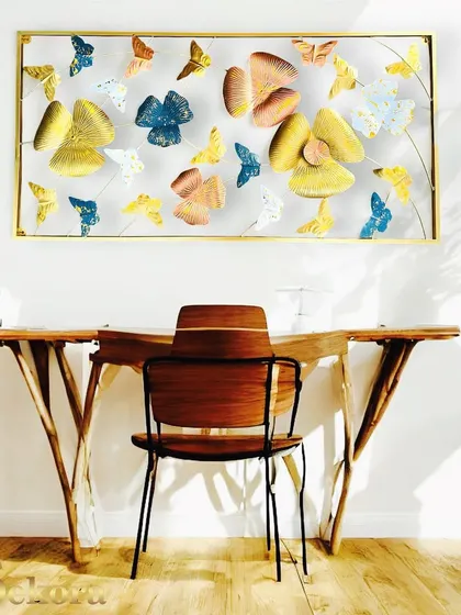 A large, framed wall sculpture filled with a flight of colorful butterflies and abstract flowers. This vibrant, three-dimensional piece brings a sense of life and color to a home office.