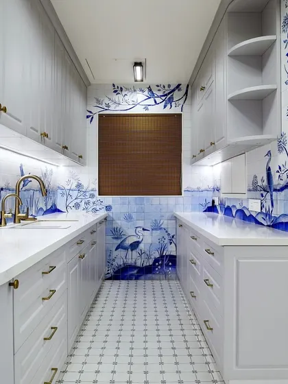 The full view of this galley kitchen showcases the immersive experience created by the hand-painted tiles. The design wraps around the room, making it feel like you are stepping into a story.