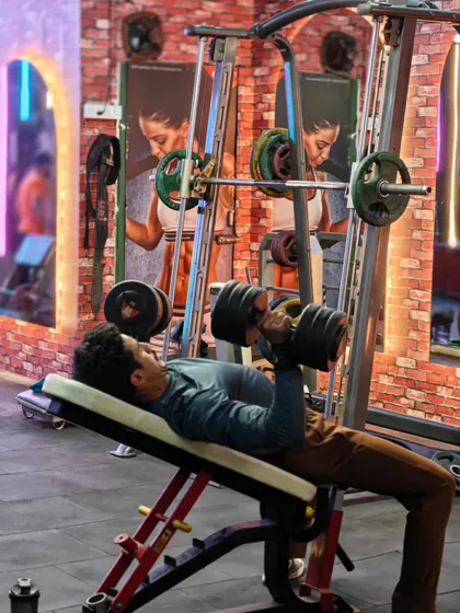 A client performs a heavy dumbbell press on an incline bench. This exercise is a cornerstone of our muscle gain plans for building upper body mass.