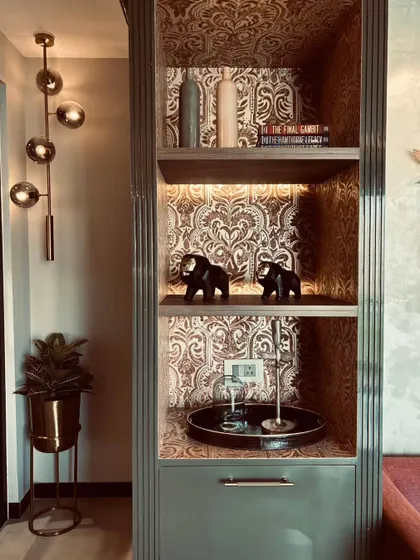 Another view of the display cabinet, showing how the internal lighting highlights the wallpaper and the decorative objects. A modern globe pendant light stands nearby, creating a stylish contrast.