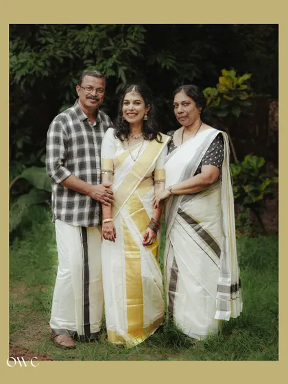 A classic family portrait with the bride in her kasavu saree, flanked by her proud parents.