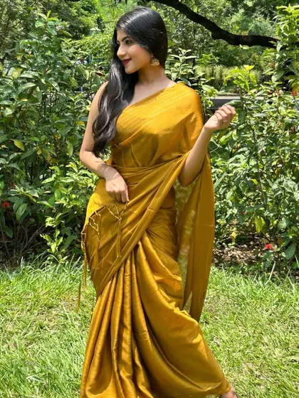 A mustard yellow saree styled for a modern, chic look. The outdoor garden setting and flowing hair create a summery, relaxed vibe, showing the versatility of the saree.
