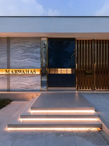 The grand entrance to a modern residence, featuring a mix of materials like marble, wood, and metal. The illuminated steps and glowing nameplate create a luxurious and welcoming first impression, showcasing our skill in hardscape and entrance design.
