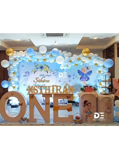 A sweet "Little Angel" first birthday theme for Sthira. The blue and white color palette, angel wing motifs, and large 'ONE' marquee letters create a heavenly celebration.