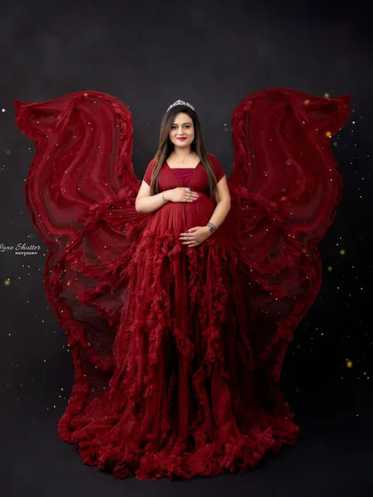 For a truly show-stopping portrait, we can create dramatic effects like these fabric wings. In a bold red gown against a dark backdrop, this style is all about celebrating the power and confidence of the mother-to-be.