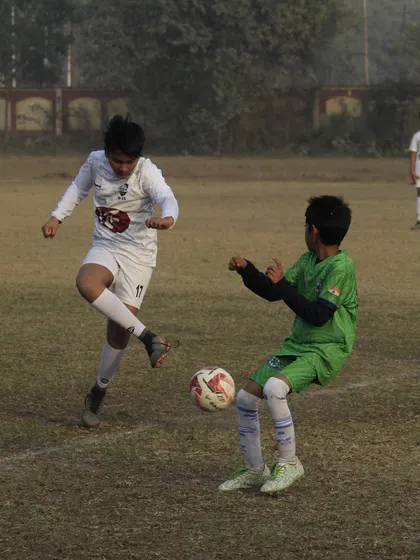 Two players challenging for the ball in a competitive youth league fixture. Every match is a learning experience.