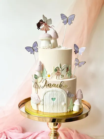 Another view of the two-tiered fairy garden cake, showing the arrangement of the toppers that create a sense of depth and magic.