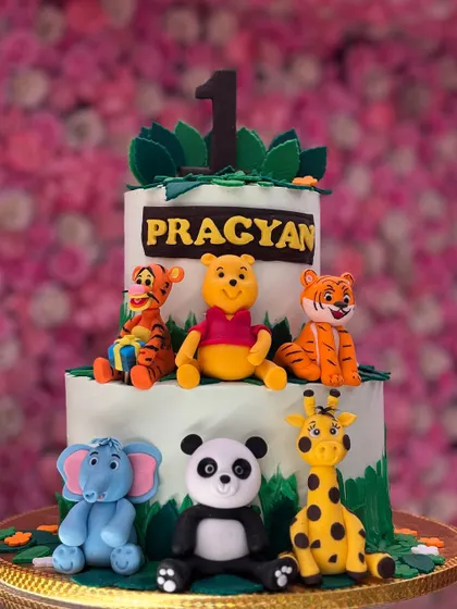 This jungle animal cake features a whole crew of cute fondant animals, including Winnie the Pooh and friends. It's perfect for a little one's first birthday celebration.