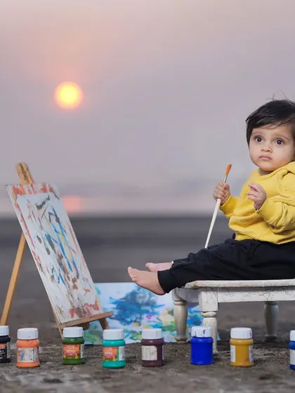 A mini artist creating a masterpiece on the beach at sunset. This themed outdoor shoot combines creativity with the beautiful natural backdrop of the sea and sky.
