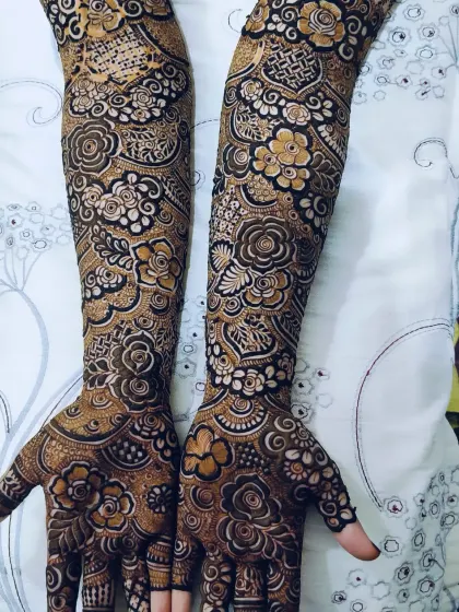 A top-down view of a complete bridal mehndi, showing how the patterns on the hands and arms work together.