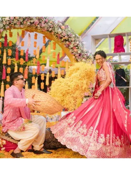 The bride twirls in her vibrant pink lehenga while the groom playfully throws petals at her. This dynamic and colorful shot is full of movement and joy.