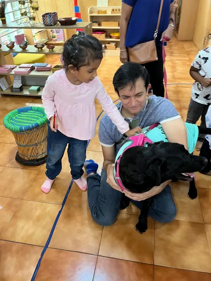 A child gently interacts with a visiting pet dog. These encounters are wonderful opportunities to teach empathy, responsibility, and how to be gentle with animals.