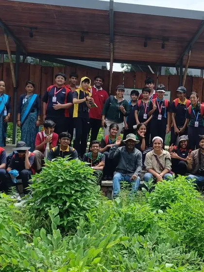 The full group of students and guides from the VIBGYOR High nature walk pose in front of the park's amphitheater.