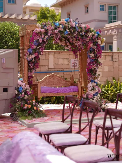 A beautifully decorated swing, a must-have for any Mehendi. The wooden swing is framed by an arch of pastel pink, blue, and purple flowers, creating a romantic and photogenic spot.