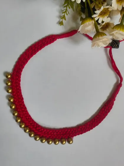 A simple yet beautiful red thread choker with golden ghungroo beads. This handmade necklace is perfect for adding a traditional touch to any outfit.