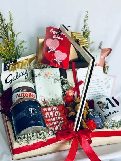 A personalized anniversary hamper with a "Happy Mahduri" theme, featuring a custom mug, Nutella, Galaxy chocolates, and a handwritten note.