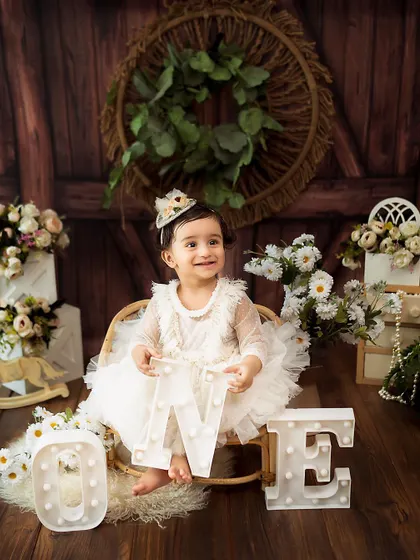 A classic first birthday shot with light-up 'ONE' letters. The soft lighting and rustic decor create a warm and celebratory mood.