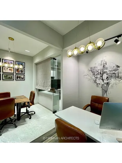 A view of our studio's conference area and principal architect's cabin. The space is defined by a custom wall mural, modern lighting, and a mix of warm and industrial materials.