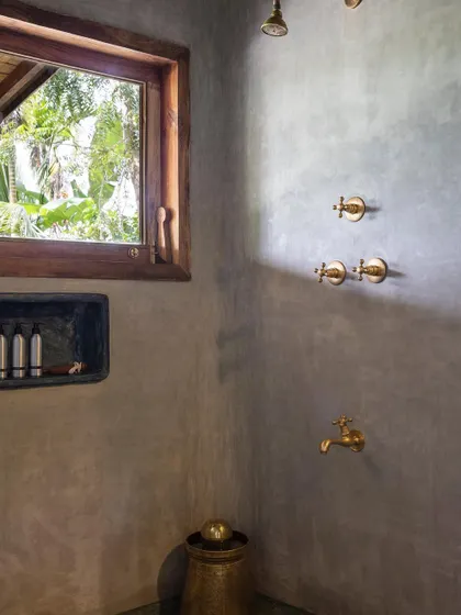 The shower in the Green Room, with its earthy polished cement walls and a window opening to the garden.