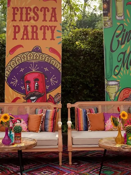 A fun and festive seating area with banners for the 'Fiesta Party' and 'Cinco de Mayo'. The decor is filled with bright colors, playful graphics, and comfortable seating for a relaxed party vibe.