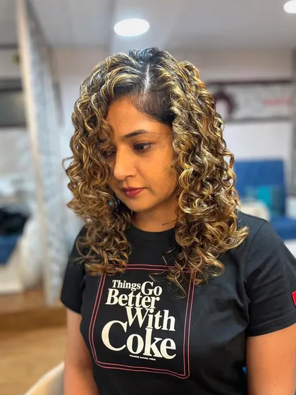 The blonde highlights create a stunning contrast and define her curls.