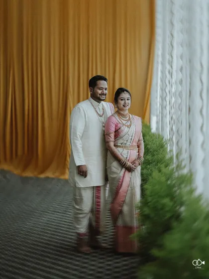 A full-length portrait of the couple standing by a window with golden curtains, looking elegant and regal.