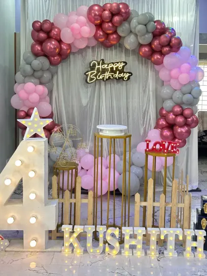 An elegant ring backdrop with pink, grey, and chrome balloons, complete with a wooden fence prop for a rustic touch.