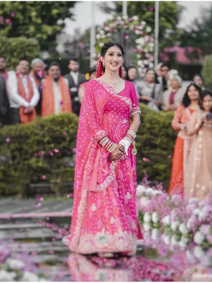 A wide shot of the bride's entrance, showing her walking down an aisle adorned with flowers, surrounded by her loved ones.