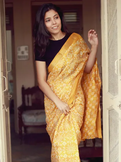 A simple and elegant pose in a yellow printed saree, showcasing a classic look suitable for a wide range of ethnic wear brands.