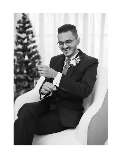 A stylish black and white portrait of the groom adjusting his cufflinks. This shot captures a quiet, classic moment of preparation.