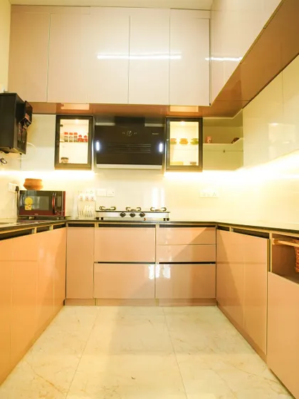 A full view of the pink and white U-shaped kitchen, showcasing the ample storage and counter space. The layout is perfect for cooking and preparation, with everything organized and within reach.