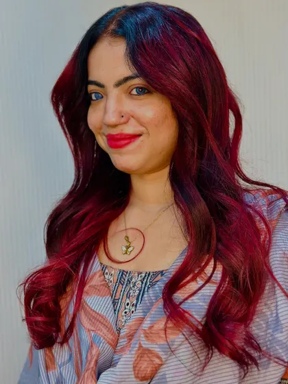 A smiling client with her new cherry red hair.