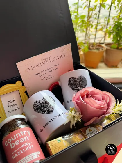 A classic anniversary hamper featuring fingerprint heart mugs, gourmet coffee, a mini photo frame, and a single red rose to say "I love you".