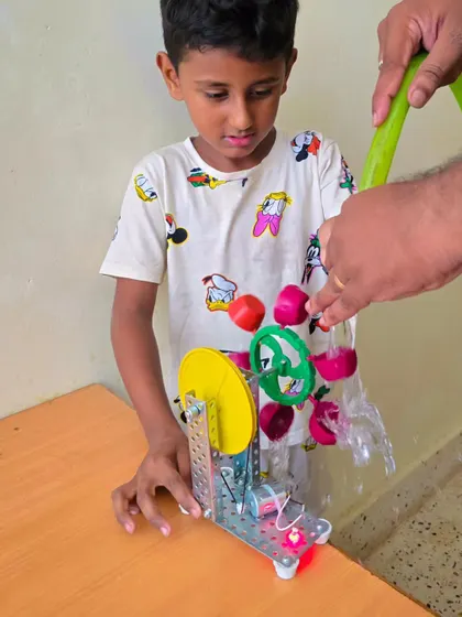 Exploring the power of water and engineering! This student is fascinated by the water turbine experiment, a perfect example of hands-on physics.