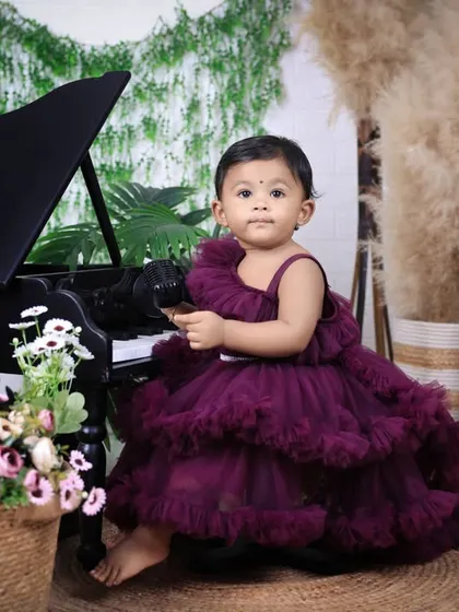 A classic portrait for a first birthday. The little girl sits elegantly by the piano, creating a timeless image to mark this special milestone.