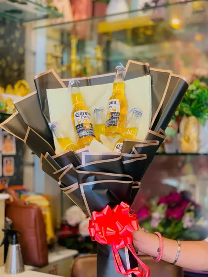 Here’s a fun and quirky option for beer lovers. This bouquet features several bottles of Corona beer, expertly arranged in a bold, black paper wrapping with a bright red bow, making it a guaranteed hit for parties and casual celebrations.