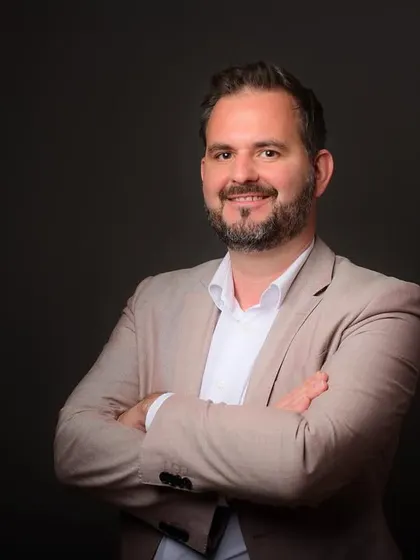 A professional headshot for a visiting business leader from Germany. The dark background and classic suit create a universally understood image of corporate professionalism.
