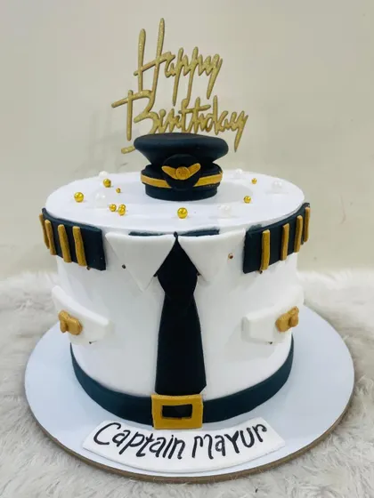 A front-on view of the crisp pilot uniform cake, showing the neat fondant work on the shirt, tie, and hat.